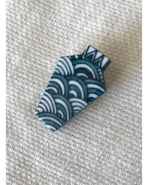 Porcelain jewellery brooch depicting Japanese waves, the symbol of tranquillity. Hand-painted in blue and white.