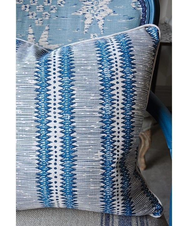 A linen striped cushion in a hand-printed, blue, zig-zag stripe design.