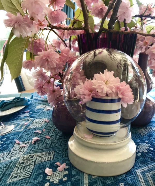 Display domes hand-crafted in Thailand, on a table with pink blossom blooms.