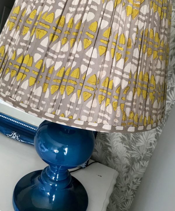 Lampshades in chartreuse and putty, block-printed in India on cotton voile, displayed here on a blue ceramic lamp base.