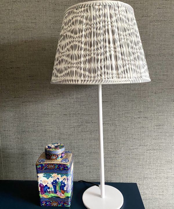 Grey patterned lampshades in. various sizes, hand block-printed in India. Styled here against a darker grey backdrop with a vintage Chinese ceramic pot.