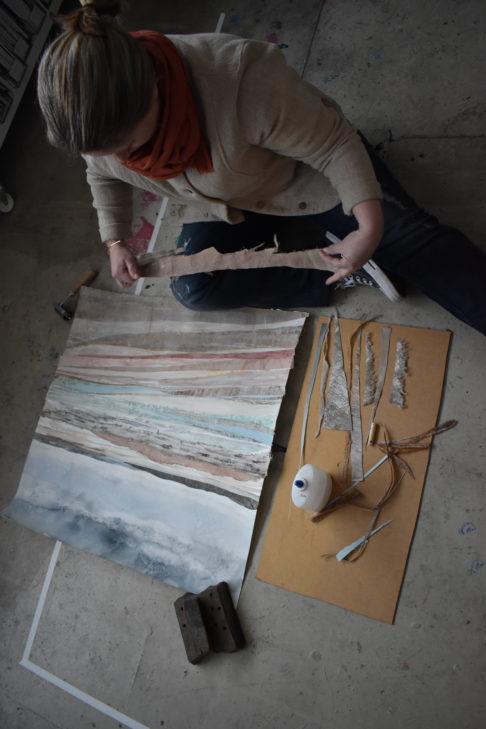 The artist, Emma Tweedie, working on the original, mixed media collage Dunes At Murlough Bay in her studio.