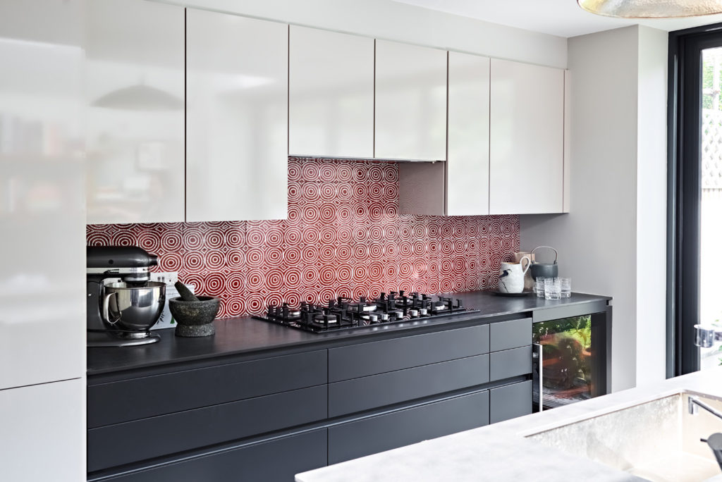 A contemporary kitchen in monochrome is the perfect foil to unusual indigenous Aboriginal art wall tiles in a warm terracotta colourway.