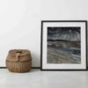 Irish wall art print Five Finger Strand is leaned against a wall next to an old-fashioned wicker picnic basket.