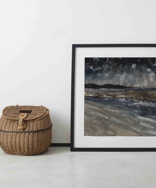 Irish wall art print Five Finger Strand is leaned against a wall next to an old-fashioned wicker picnic basket.