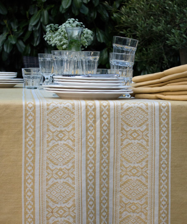 Detail of an elegant, Hungarian-folk-inspired tablecloth in soft yellow.