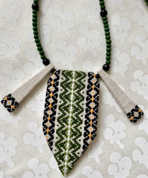 An embroidered textile necklace in green and black.