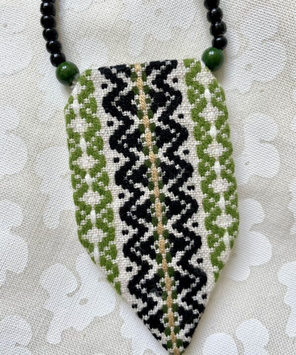 A chic, embroidered panel necklace with a beaded ribbon fastening.