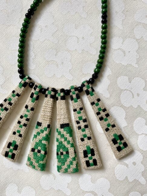 A green bib necklace showcasing a vintage Slovenian embroidered textile.