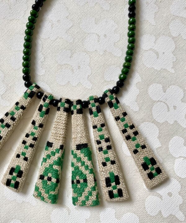 A green bib necklace showcasing a vintage Slovenian embroidered textile.