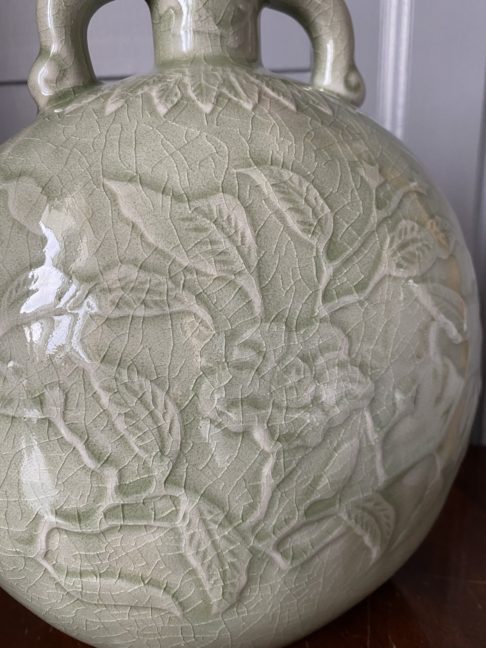 Close up detail of a hand-decorated celadon pottery pot.