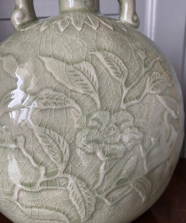 Close up detail of a hand-decorated celadon pottery pot.