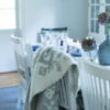 A pale grey Icelandic bind rune blanket on the back of a dining chair in a Scandinavian feel dining room setting.