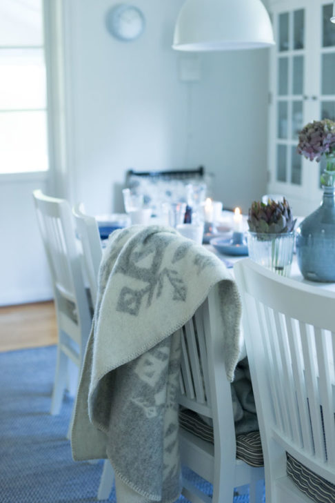 A pale grey Icelandic bind rune blanket on the back of a dining chair in a Scandinavian feel dining room setting.