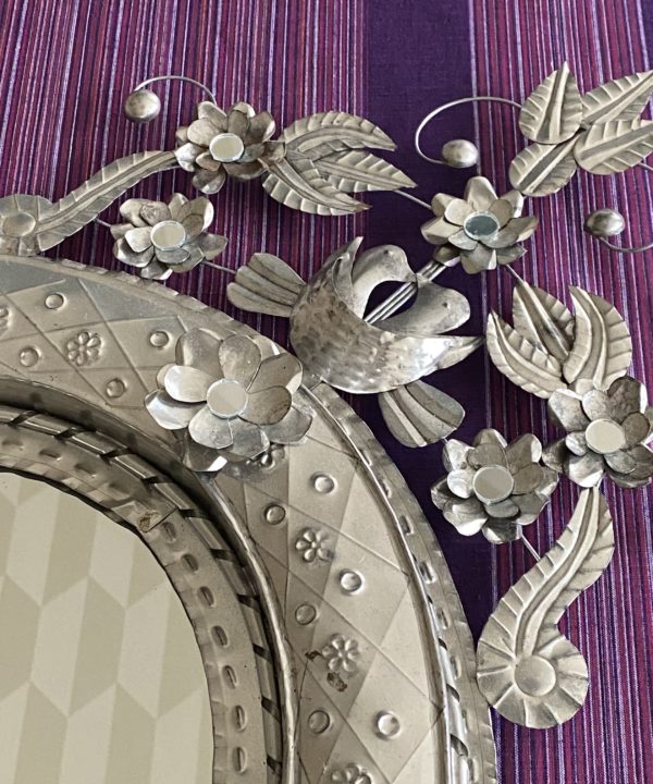 A decorative Mexican mirror against a purple striped backdrop.