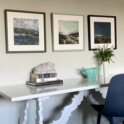 Three Northern Ireland prints hung above a desk.