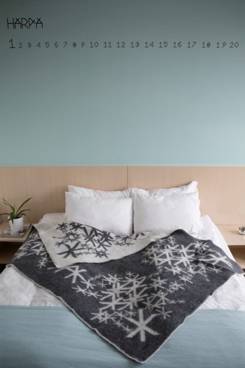 A grey bind rune blanket styled on a bed in a modern apartment.