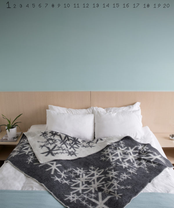 A grey bind rune blanket styled on a bed in a modern apartment.