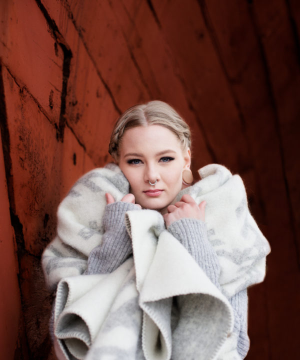 A model wrapped up in our light grey blanket throw with Nordic bindrune symbols that reference love.