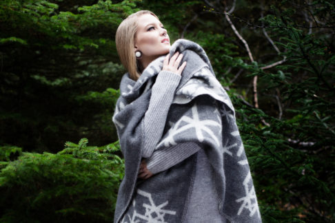 Grey blanket throw with Nordic bindrunes on a model against a forest backdrop.