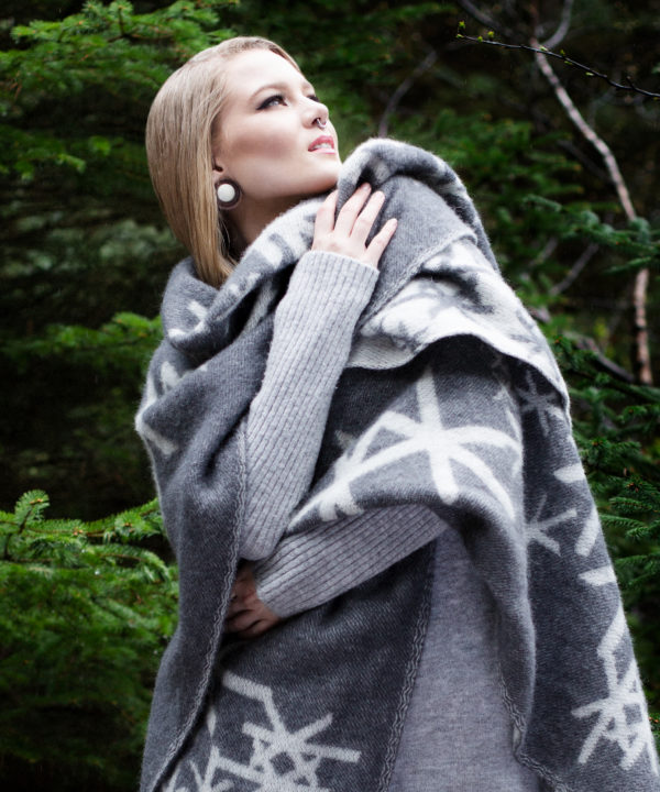 Grey blanket throw with Nordic bindrunes on a model against a forest backdrop.