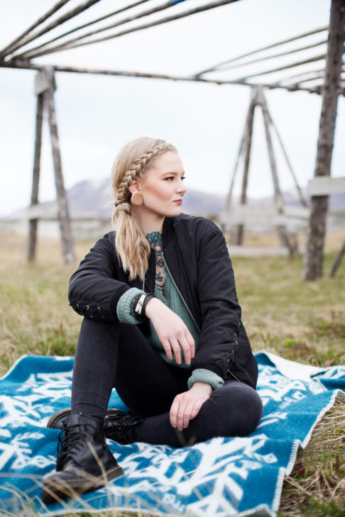 A model sitting on a teal blanket throw in the Icelandic countryside.