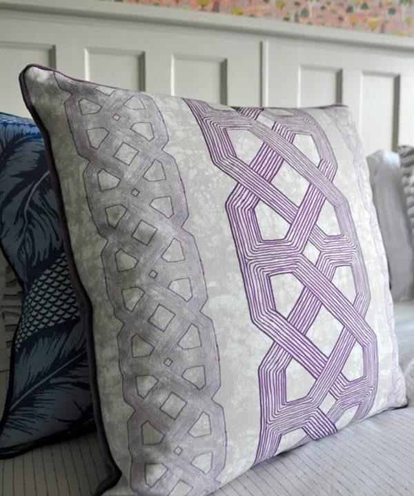 Purple lattice print African tribal cushion on a bed.