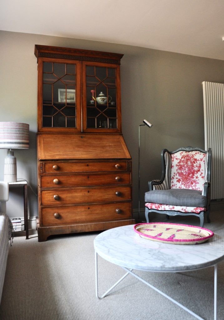 Lockdown decorating might involve shifting furniture around and experimenting. This room displays an eclectic mix of mahogany dresser, floral upholstered bergère chair and modern marble coffee table.