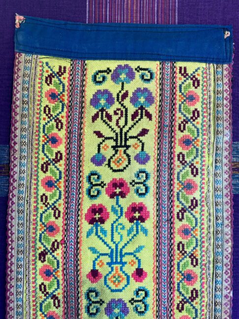 Fabric wall art showing a section of an embroidered Thai costume panel.