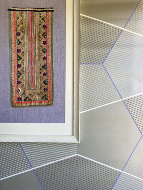 Unique wall art showing a vintage, Thai framed textile with beading against modern wallpaper.