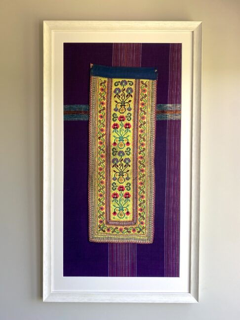 A framed, vintage Thai textile against purple cotton.