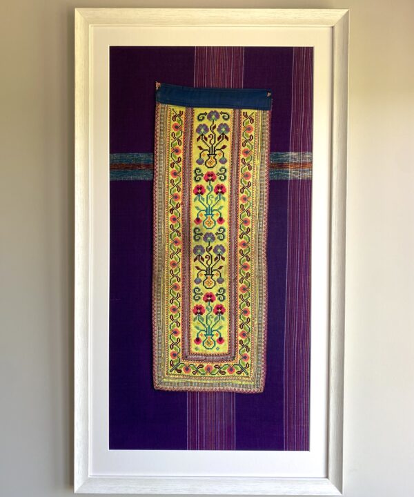 A framed, vintage Thai textile against purple cotton.