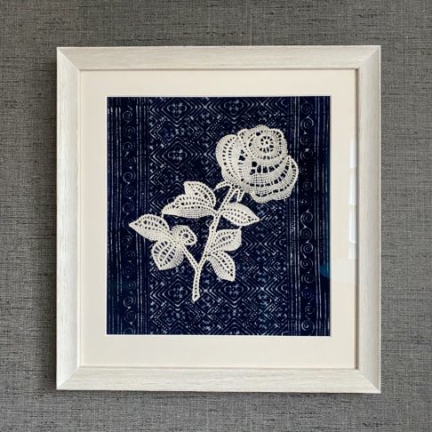 Framed textile art depicting a lace rose against an indigo textile backdrop.