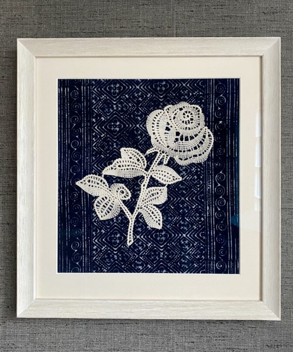 Framed textile art depicting a lace rose against an indigo textile backdrop.