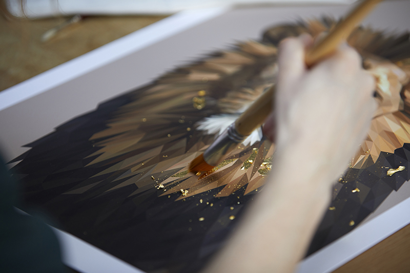 Detail shot of Talia Giles applying a gold leaf finish to the lion portrait.