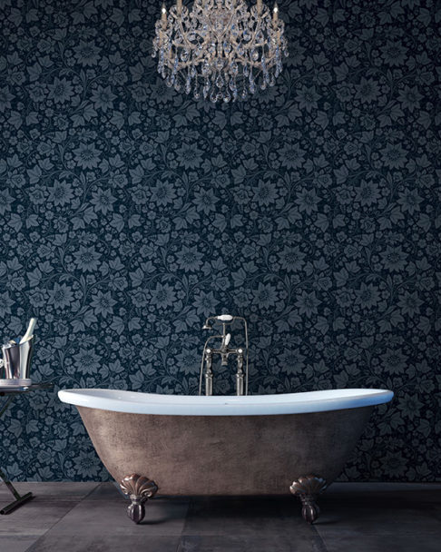 Dark grey, floral wallpaper used a the backdrop to a bathroom with a free-standing tub.