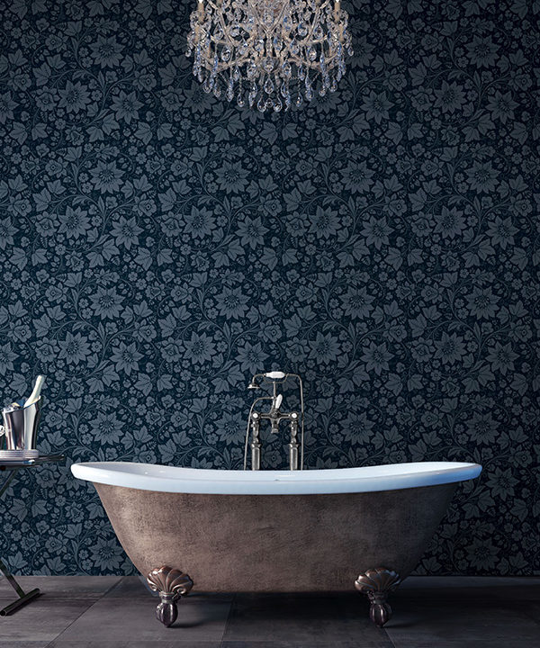 Dark grey, floral wallpaper used a the backdrop to a bathroom with a free-standing tub.