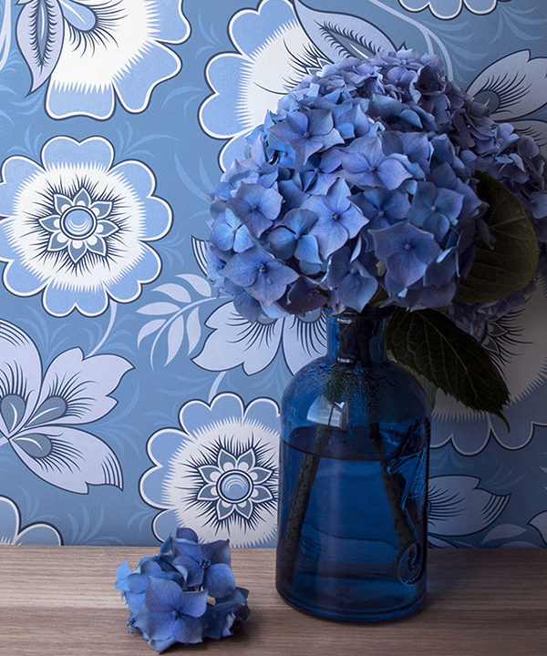 Floral folk art wallpaper in blue with hydrangeas in the foreground.