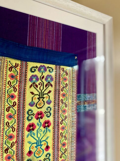 Detail of a vintage embroidered panel from Thailand in yellow framed as wall art.