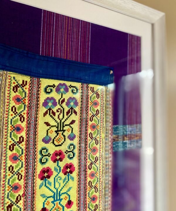 Detail of a vintage embroidered panel from Thailand in yellow framed as wall art.