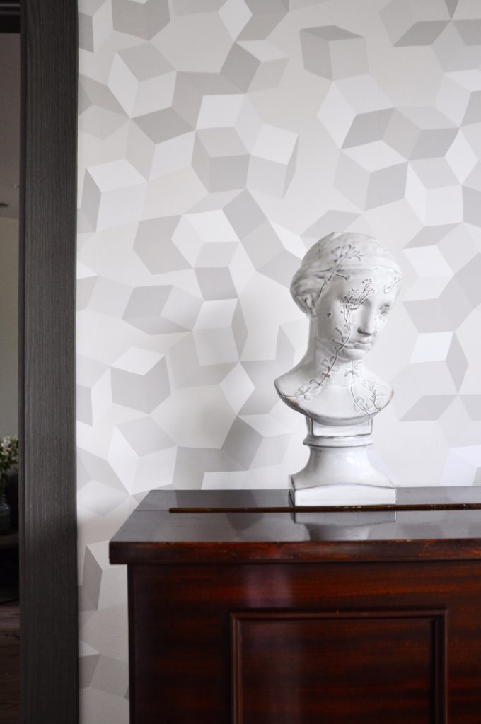 A ceramic bust from the Yarnnakarn studio displayed in front of geometric wallpaper by Cole & Son.