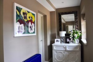 A neutral hallway is accented by blue, burgundy and yellow decorative accessories and radiator!