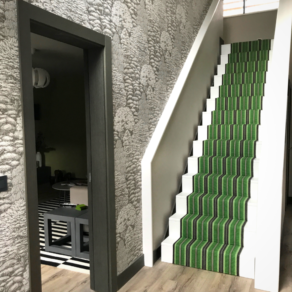 A vibrant, green, woven, striped, stair runner in a modern grey-toned hallway.