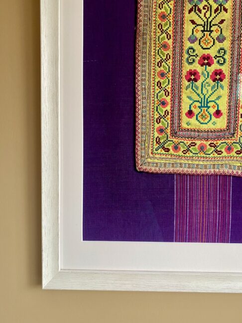 Fabric wall art comprising a vintage embroidered panel from northern Thai craftspeople framed against South East Asian dress cotton.