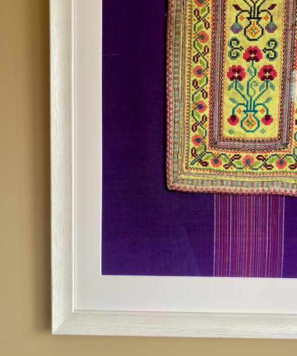 Fabric wall art comprising a vintage embroidered panel from northern Thai craftspeople framed against South East Asian dress cotton.