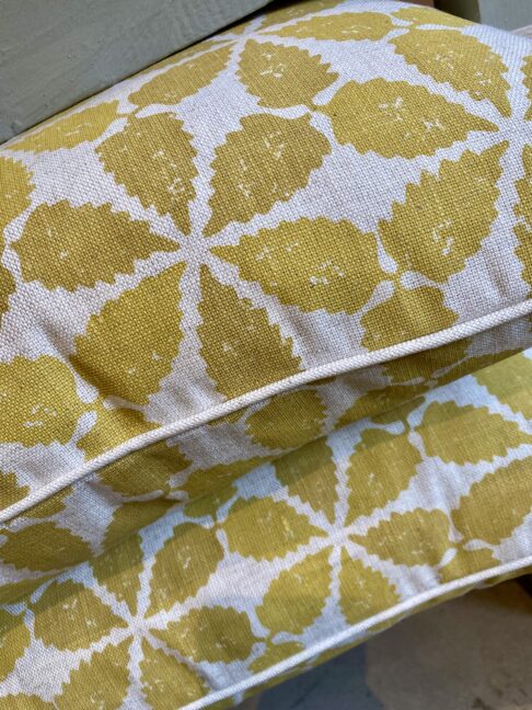 Muted yellow, hand-printed linen cushions with a Moroccan-inspired design and simple neutral piping..