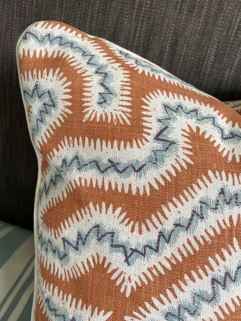 Detail of a burnt orange cushion with blue accents hand-printed on linen.