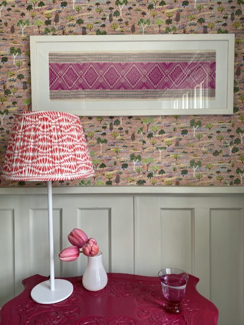 Pretty, cherry red lampshades for table lamps shown here on a pink, painted vintage table beside a four poster bed.