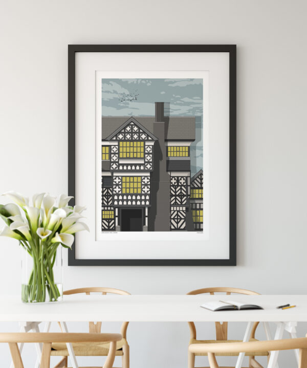 A print of Tudor manor house Little Moreton Hall, Cheshire. The print is hung on a wall in a modern, dining room setting.