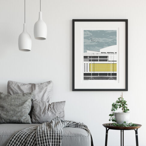 A framed artwork of the Royal Festival Hall on the wall of a contemporary sitting room space, above a side table.